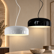 Aluminum Chic Round Pendant Lamp in white and black, two glossy dome pendants lit above a stone table in a warm modern interior