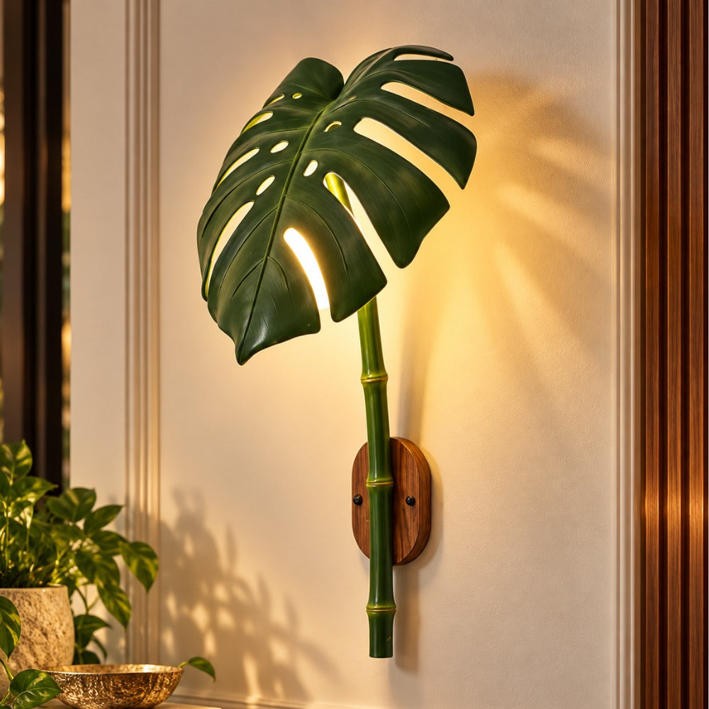 Monstera Leaf Bamboo Outdoor Wall Lamp on a wall beside a plant