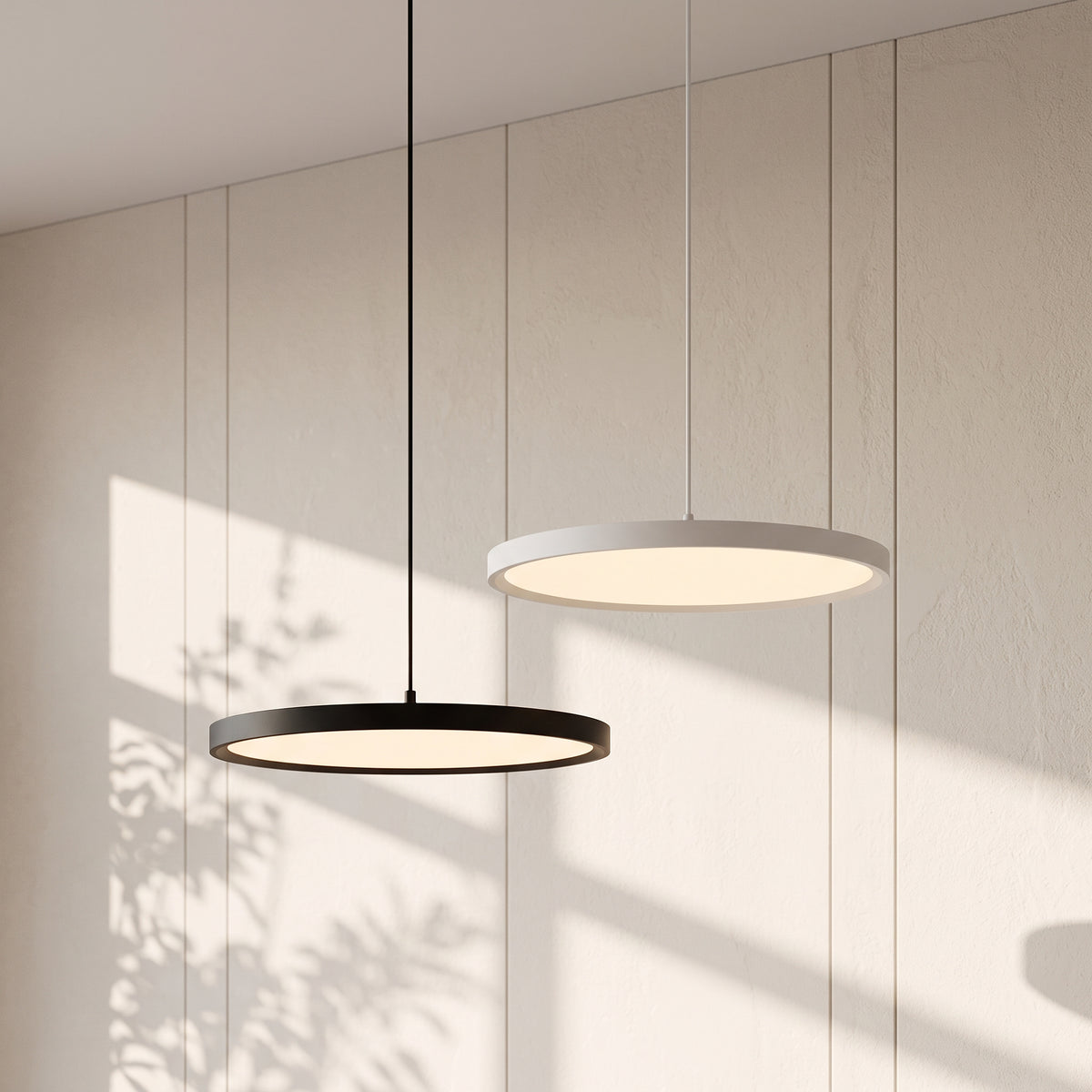 Round Metal Disc LED Pendant Lights black and white round metal disc LED pendant lights glowing against a sunlit white wall