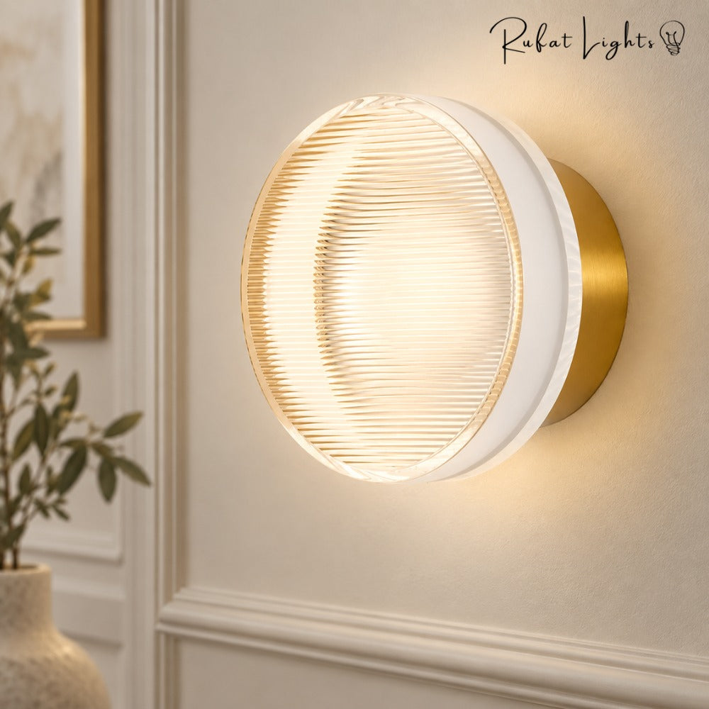 Round Textured Glass Wall Lamp in gold close-up on a white panelled wall