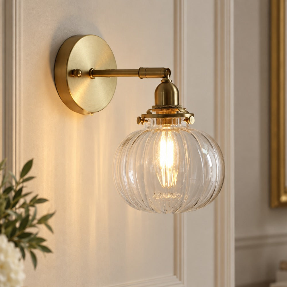 Textured Glass Globe Wall Lamp with ribbed clear glass globe and brass arm on a panelled wall