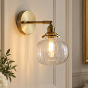 Textured Glass Globe Wall Lamp with ribbed clear glass globe and brass arm on a panelled wall